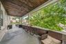 Covered porch featuring a wood-plank ceiling, concrete flooring, and slatted wood railing