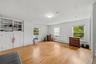 Large bedroom with hardwood floors, multiple windows, and built-in storage.