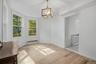 White walls, wood-finish flooring, and a contemporary chandelier
