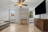 Light wood-finish flooring, a white stone-clad fireplace, and multiple windows