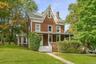 Victorian-style residence featuring brown siding with white trim, a covered front porch, and a prominent front gable