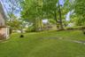Expansive green lawn with mature trees and a side bay window on the residence