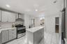 Modern kitchen featuring white subway tile backsplash, stainless steel range and hood, light-toned cabinetry, a central island, and large format floor