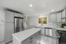 Kitchen featuring gray shaker-style cabinetry, a central island with a light-toned countertop, a subway tile backsplash, and stainless steel appliance