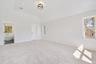 Unfurnished bedroom featuring light carpet, vaulted ceiling, and multiple windows