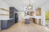 Kitchen with a center island, stainless steel appliances, light hardwood / wood-style floors, wall chimney range hood, and decorative light fixtures