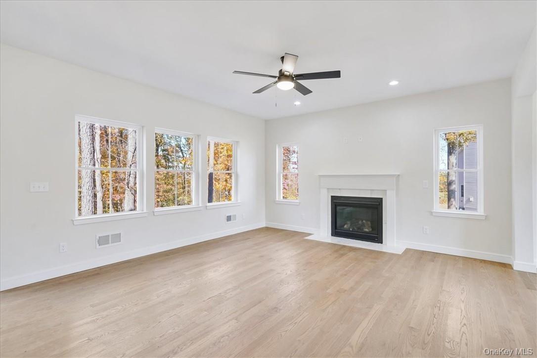 Unfurnished living room featuring a healthy amount of sunlight, ceiling fan, and light hardwood / wood-style flooring