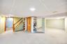 Below grade area with stairs, a drop ceiling, and carpet floors