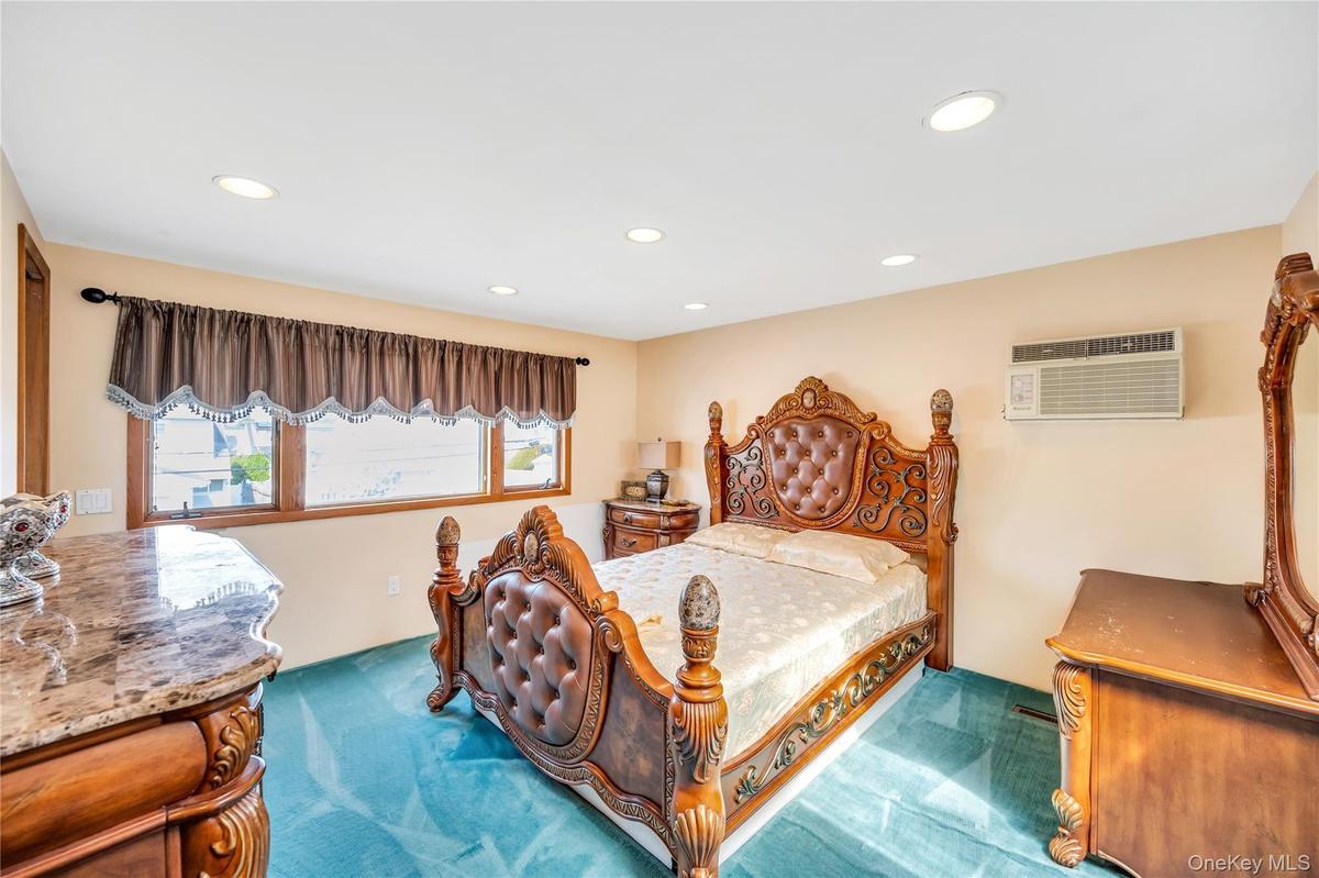 Carpeted bedroom with recessed lighting and an AC wall unit