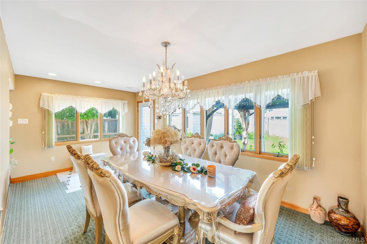 Carpeted dining area with a chandelier and recessed lighting