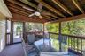 Screened-in deck featuring a wood-finish ceiling with exposed beams, ceiling fan, and a light wood-finish railing system