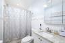 Bathroom featuring a single vanity with a light-toned countertop, white cabinetry, a rectangular undermount sink, and a mirrored medicine cabinet