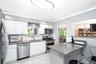 White shaker cabinetry, stainless steel appliances, granite countertops, subway tile backsplash, and tile flooring