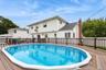 Permitted partially inground pool with fence and trek decking surrounding (virtually enhanced)