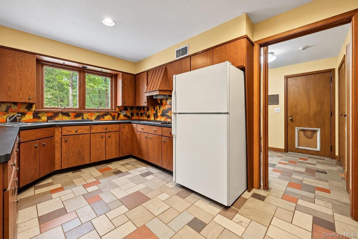 Wood cabinets, stone floor, door on right leads to laundry room, powder room, pantry and backyard.