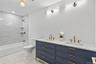 Bathroom with shower / washtub combination, double vanity, and recessed lighting