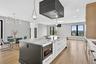 Kitchen with light stone counters, pendant lighting, premium range hood, light wood-style floors, and recessed lighting