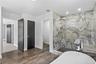 Bathroom featuring a freestanding bath, a marble finish shower, recessed lighting, and dark wood-style flooring