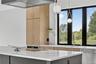 Kitchen with light brown cabinets, stainless steel dishwasher, light stone countertops, and gray cabinets