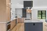 Kitchen featuring light stone countertops, hanging light fixtures, light wood-style flooring, a kitchen island, and oven