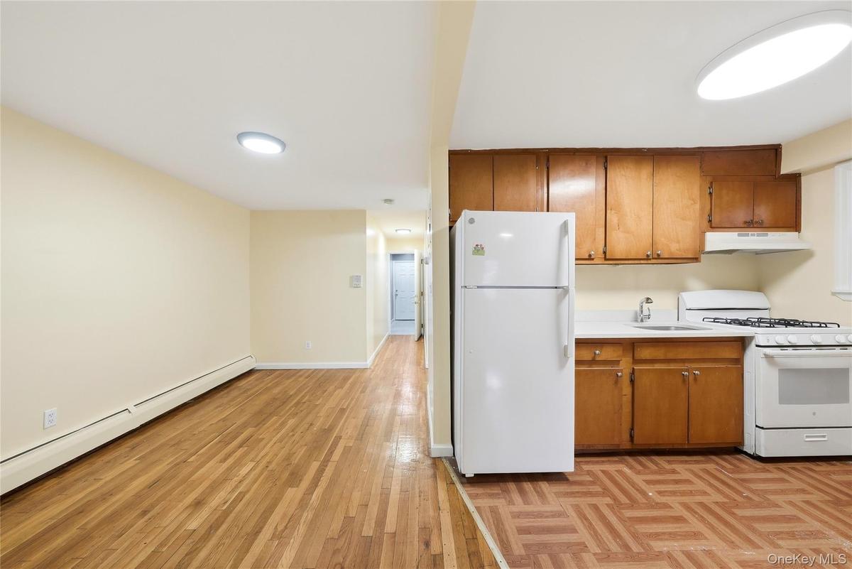 Kitchen featuring wood cabinetry, white appliances, and a stainless steel sink