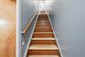 Wooden staircase with a natural wood handrail and light blue painted walls