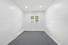 Recessed ceiling lighting, white painted walls, single window with blinds, baseboard heating unit, and gray carpeted flooring