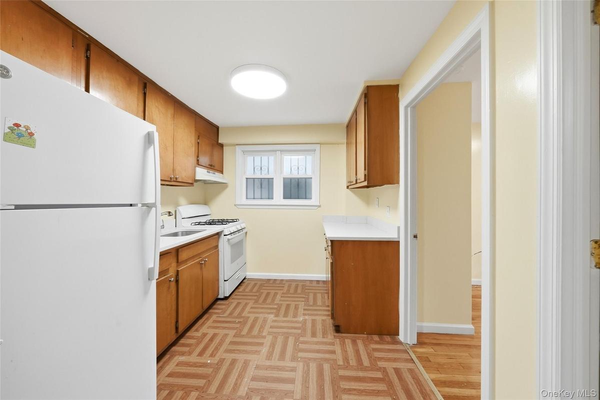 Compact kitchen with a built-in range, overhead cabinetry, and patterned flooring