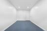 Recessed lighting illuminates the room, featuring white walls and a blue carpeted floor