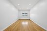 Hardwood flooring, recessed ceiling lighting, a window with an awning, and pristine white walls