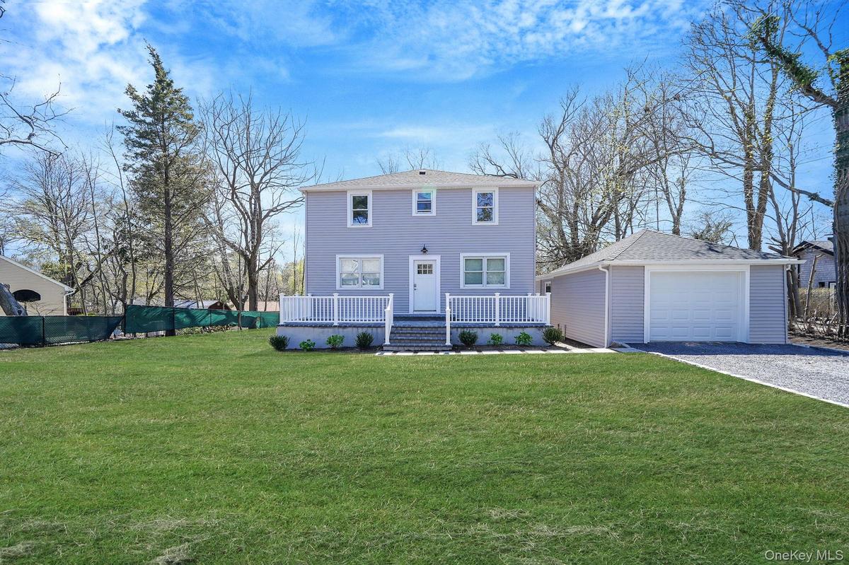 Colonial-style house with an outdoor structure, a detached garage, covered porch, driveway, and a front lawn