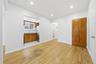 Wood-finish flooring throughout, recessed lighting, and a kitchen alcove with wood cabinetry and a stainless steel refrigerator