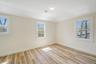 Spare room with healthy amount of natural light, baseboards, and wood finished floors