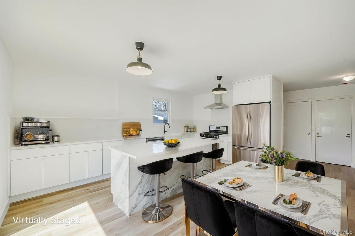 Kitchen featuring stainless steel appliances, modern cabinets, a kitchen breakfast bar, white cabinetry, and pendant lighting