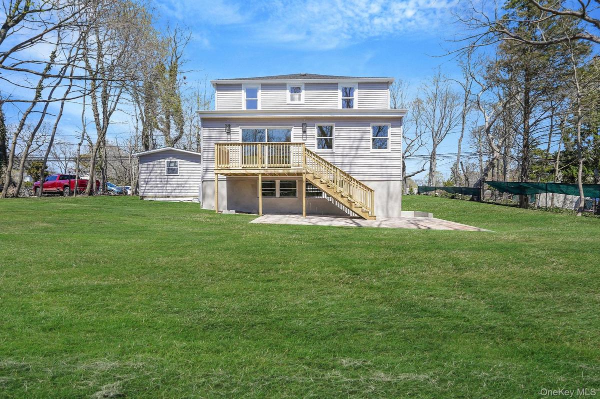 Rear view of house with a deck, stairs, a yard, and a patio area