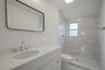 Full bath with marble look tile flooring, toilet, vanity, and a marble finish shower