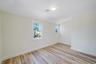 Unfurnished room featuring baseboards, light wood-style floors, and lofted ceiling
