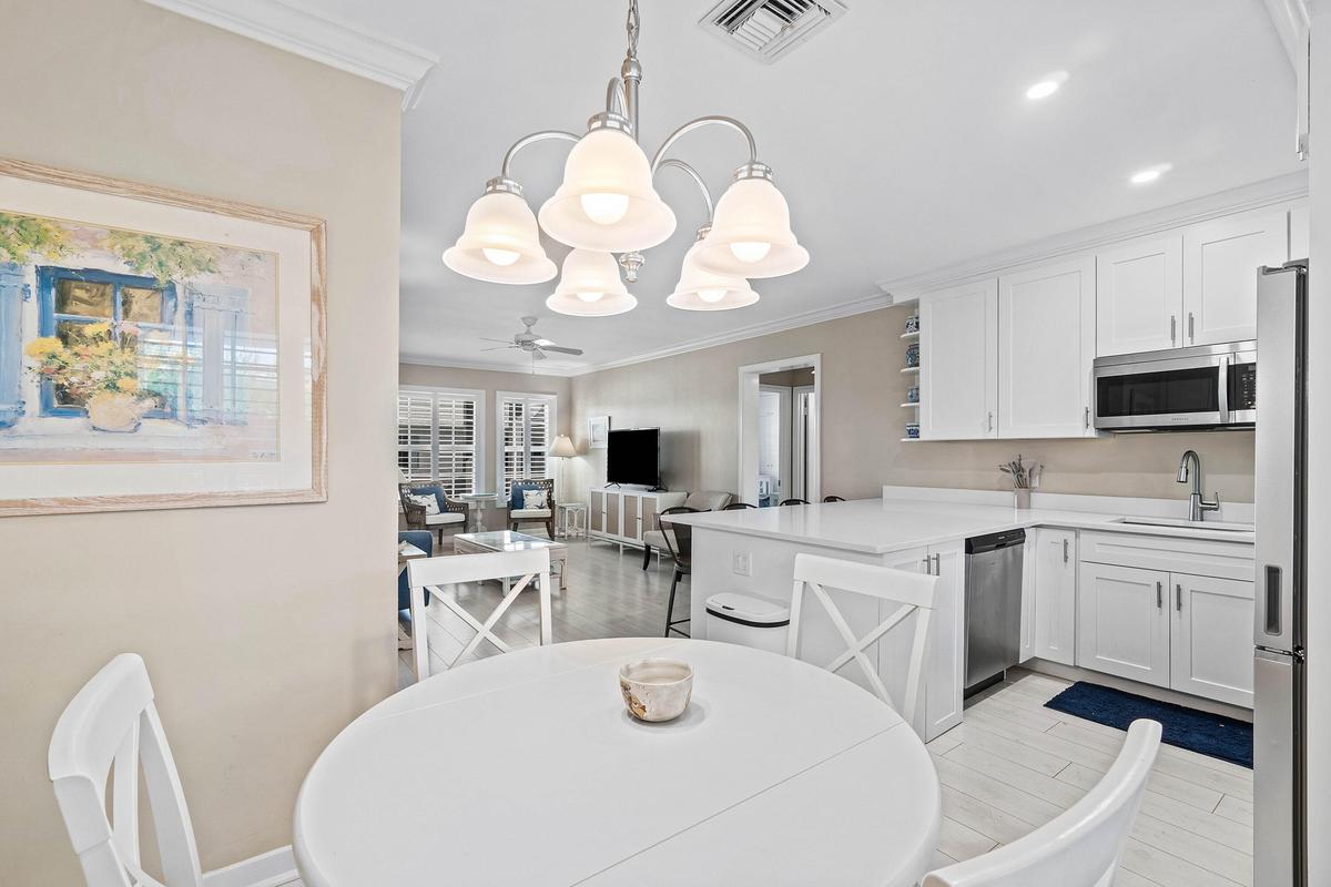 Bright kitchen featuring white cabinetry, stainless steel appliances, corner shelving, and a large breakfast bar with white surface countertops