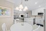 Bright kitchen featuring white cabinetry, stainless steel appliances, corner shelving, and a large breakfast bar with white surface countertops