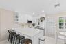 Bright kitchen featuring white cabinetry, stainless steel appliances, corner shelving, and a large breakfast bar with solid surface countertops