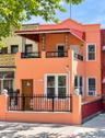 Two-story residential facade with an orange exterior, featuring a second-level balcony with black wrought iron railing and an awning