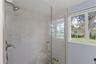 Updated bathroom features a glass-enclosed walk-in shower with large-format tile and pebble-style shower flooring.