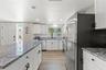 Another view highlights the kitchen’s extensive cabinetry, stainless steel appliances, granite surfaces, and luxury vinyl plank flooring.