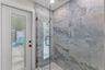 Beautifully tiled walk-in shower with frameless glass enclosure, oversized tile, and a rainfall-style showerhead.
