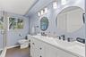 Updated bathroom with dual sinks, modern fixtures, generous vanity storage, and a glass-enclosed walk-in shower.