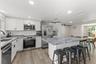 Renovated kitchen with white cabinetry, granite countertops, stainless steel appliances, and an oversized island with seating for four.