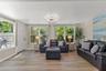 A wall of windows fills the room with natural light while overlooking the surrounding tropical landscaping.