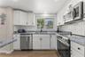 White cabinetry, granite countertops, subway tile backsplash, stainless steel appliances, and a window above the kitchen sink.