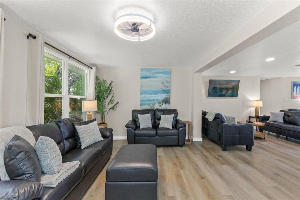 Large windows bring natural light and tropical views into this spacious living area.