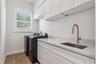 The laundry room includes a washer, dryer, utility sink, and upper and lower cabinetry.